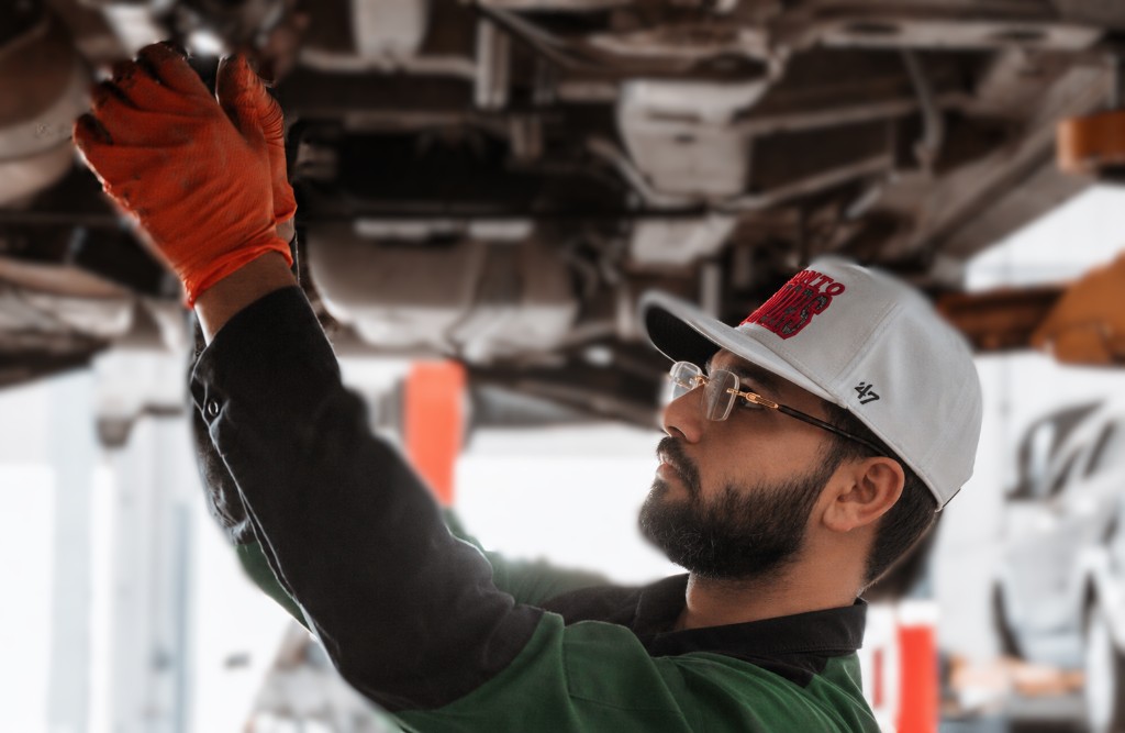EcoautoworX mechanic performing undercarriage service on a lift
